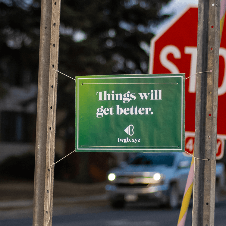 A green sign with the phrase 'Things will get better' hung on a street sign.